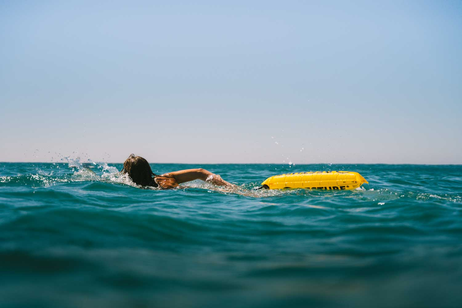 Frau schwimmt im offenen Gewässer im Meer mit einer Restube active Schwimmboje