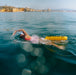 Triathlete drags inflated restube swim buoy behind her while crawl swimming in the sea
