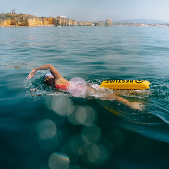 Triathlete drags inflated restube swim buoy behind her while crawl swimming in the sea