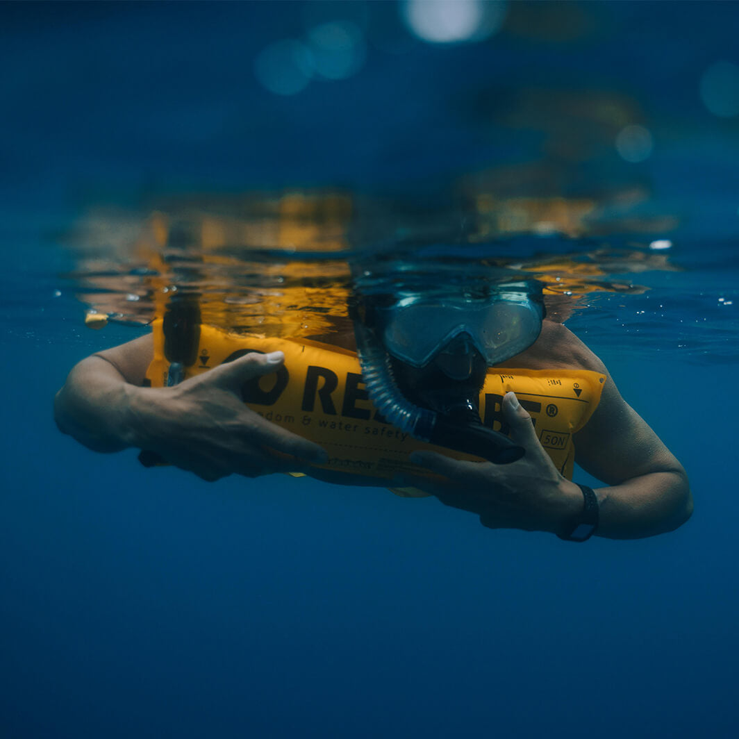 Swimmer snorkeling relaxed leaning over restube buoy