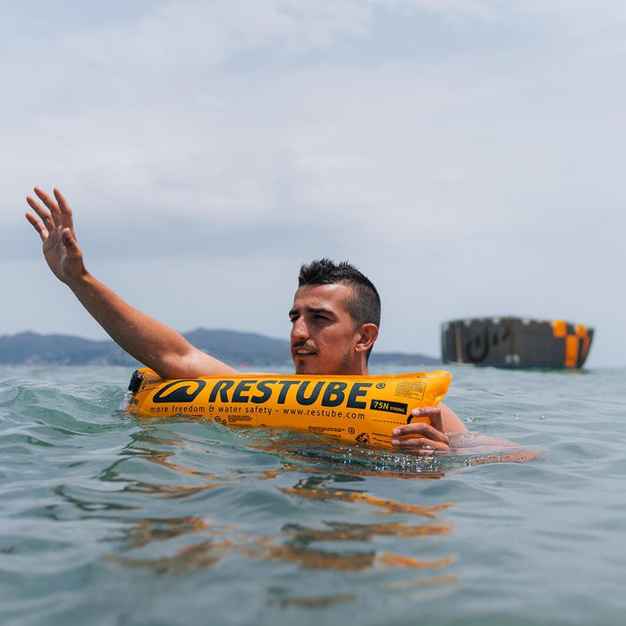 Swimmer on inflated restube buoy creates attention by waving